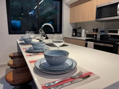 a kitchen with a table with plates and wine glasses at Vistas del Bosque Jacó in Jacó
