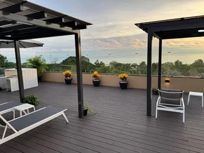 a deck with chairs and tables on a roof at Vistas del Bosque Jacó in Jacó