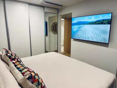 a bedroom with a bed and a tv on a wall at Vistas del Bosque Jacó in Jacó