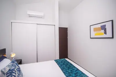 a bedroom with a white bed with a blue blanket at Relaxing Beach Oasis - Gated Community with Pool - Mini Golf - Walking Distance to Beach in Jacó