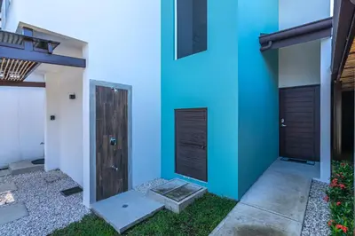 a house with a blue wall and a door at Relaxing Beach Oasis - Gated Community with Pool - Mini Golf - Walking Distance to Beach in Jacó