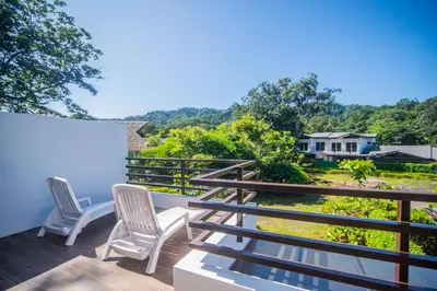 a balcony with two chairs and a view of a yard at Relaxing Beach Oasis - Gated Community with Pool - Mini Golf - Walking Distance to Beach in Jacó