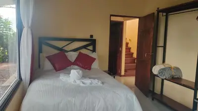 a bedroom with a bed with red pillows and a window at Monteverde Beaumont in La Cruz