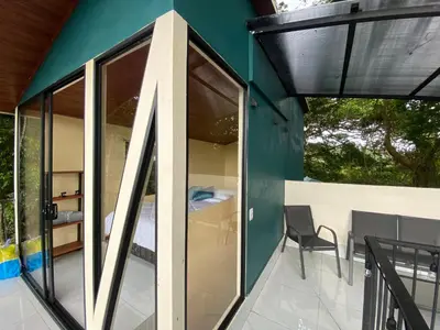 a house with glass doors and a chair on a balcony at Monteverde Beaumont in La Cruz