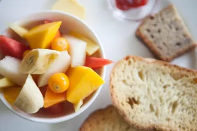 a bowl of fruit and bread and a bowl of soup at Bajo el Arbol B&B in Santa Teresa Beach