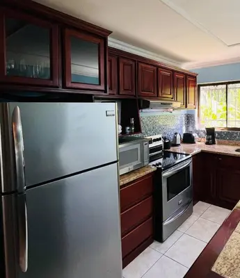 a kitchen with a stainless steel refrigerator and wooden cabinets at Apartments for vacation by the Pasifc in Coco