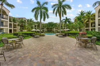a courtyard at the resort with tables and chairs and palm trees at Elegant Condo in High-End Resort Community with Pool and Beach Club Access in Coco
