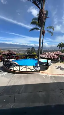 a large swimming pool with a palm tree and umbrellas at Casa Escazu Overlook in San Antonio