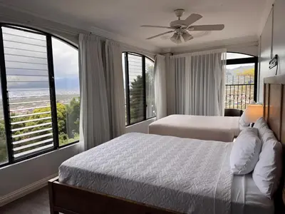 a bedroom with two beds and large windows at Casa Escazu Overlook in San Antonio