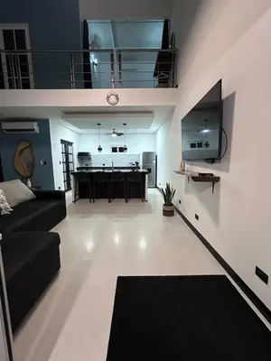 a living room with a black couch and a kitchen at Loft en San José de pinilla avellanas guanacaste in San José Pinilla