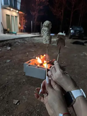 two people holding food on sticks in front of a fire at Loft en San José de pinilla avellanas guanacaste in San José Pinilla