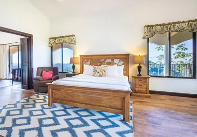 a bedroom with a bed and a chair and windows at Luxury Villa Bijagual Costa Rica in Carara