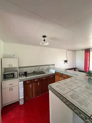 a kitchen with wooden cabinets and a red floor at Cabaña cielo celeste in Rio Celeste