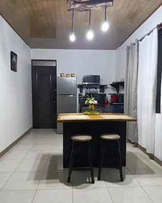a kitchen with a island with two stools in it at Coral House Fortuna in Tanque