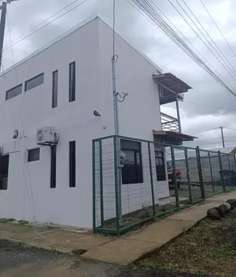 a white building with a green fence in front of it at Coral House Fortuna in Tanque