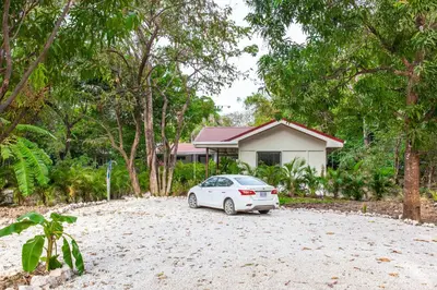 a white car parked in front of a house at Nosara Beach Cabins in Nicoya