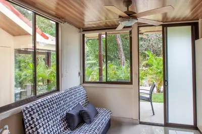 a living room with a couch and a ceiling fan at Nosara Beach Cabins in Nicoya