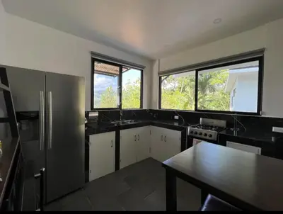 a large kitchen with black counter tops and windows at Casa Cascada La Roca in Sámara