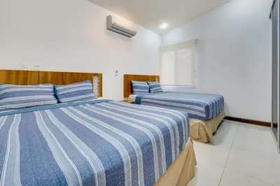 a bedroom with two beds with blue and white striped sheets at Casa Fabali in Tamarindo