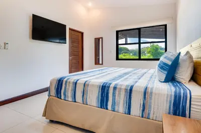 a bedroom with a bed with a tv and a window at Casa Fabali in Tamarindo