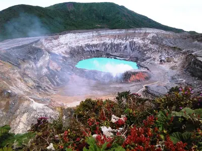a hole in the side of a mountain with a blue lake at Supercostarica in Grecia