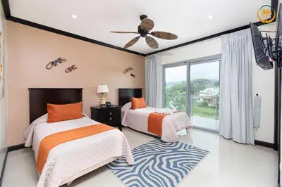 a bedroom with two beds and a ceiling fan at Modern Condominium Beachfront Jaco Beach, Diamante del Sol in Jacó