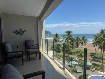 a room with a balcony with a view of the beach at Modern Condominium Beachfront Jaco Beach, Diamante del Sol in Jacó