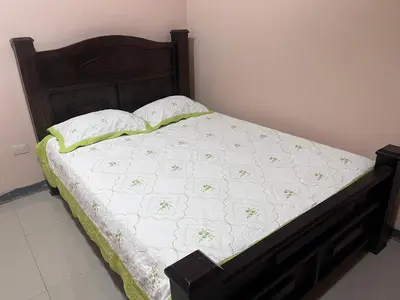 a bed with a wooden headboard and a white bedspread and pillows at Apartamento Río Niño in Upala