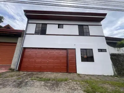 a garage with two red doors on a house at Apartamentos casco in Heredia