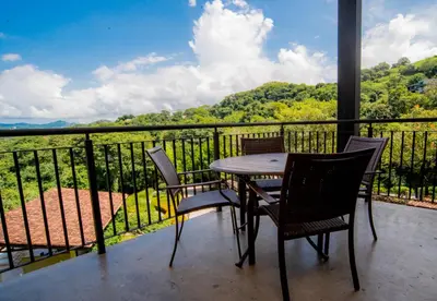 a table and chairs on a balcony with a view at Spacious 2BR Condo with Partial Ocean View- Roble Sabana- Reserva Conchal in Playa Conchal