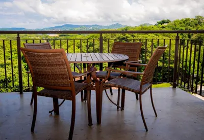 a wooden table and chairs on a balcony with a view at Spacious 2BR Condo with Partial Ocean View- Roble Sabana- Reserva Conchal in Playa Conchal