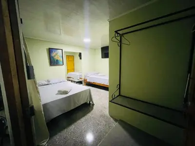 a bedroom with two beds and a door to a room at Cabinas Marielos in Sarapiquí