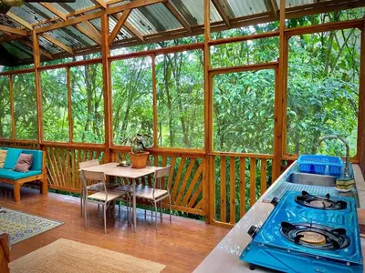 a screened in porch with a stove and a table at River Cabin 1BR Breathtaking Chirripó Retreat in Tapantí