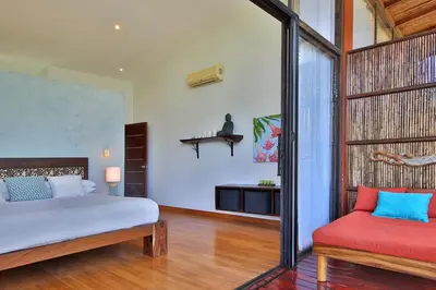 a bedroom with a bed and a red chair at Stef Surf Villa El Delfin in Potrero