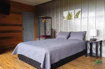 a bedroom with a bed and a table with a lamp at Hospedaje Oropéndola in Quesada