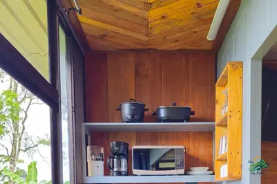 a kitchen with two pots and a microwave on a shelf at Hospedaje Oropéndola in Quesada