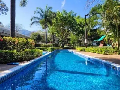 a large blue swimming pool with trees and bushes at Walk to Downtown Santa Ana, Near Airport, Lush Gardens, Pool, King Bed, Security in Santa Ana