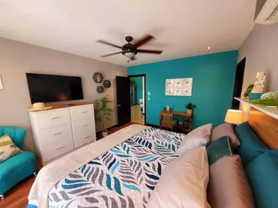 a bedroom with a bed and a couch and a flat screen tv at Walk to Downtown Santa Ana, Near Airport, Lush Gardens, Pool, King Bed, Security in Santa Ana