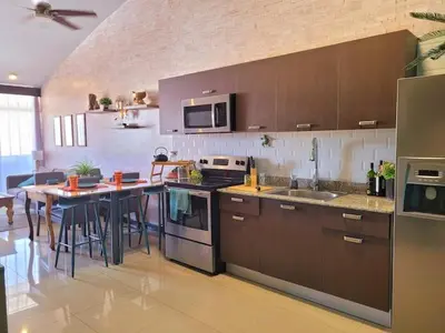a kitchen with brown cabinets and a table in it at Walk to Downtown Santa Ana, Near Airport, Lush Gardens, Pool, King Bed, Security in Santa Ana