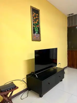 a living room with a flat screen tv on a yellow wall at Pura Vida Stay Liberia in Liberia