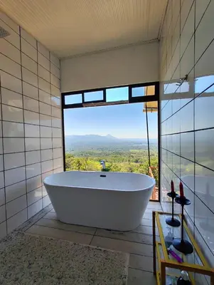 a bath tub in a bathroom with a large window at Hygge House with a view of the Arenal Volcano and the San Carlos Plain in Vieja