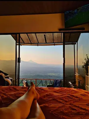 a person laying on a bed with a view at Hygge House with a view of the Arenal Volcano and the San Carlos Plain in Vieja