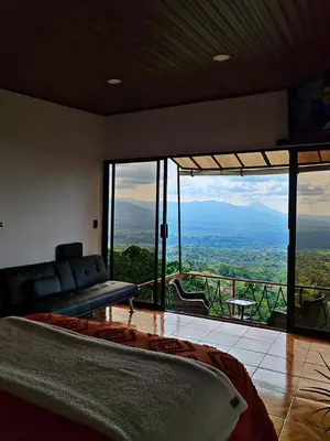 a bedroom with a bed and a balcony with a view at Hygge House with a view of the Arenal Volcano and the San Carlos Plain in Vieja