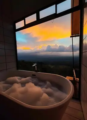 a bath tub in front of a window with a view at Hygge House with a view of the Arenal Volcano and the San Carlos Plain in Vieja