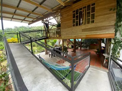 a balcony of a house with a hammock on it at Cabin -Treehouse La Tigra in San Gerardo