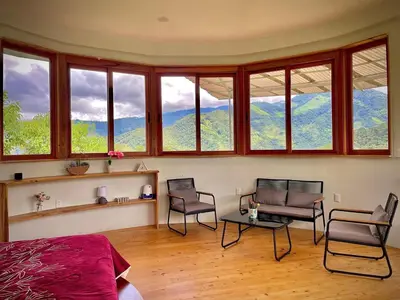 a bedroom with two chairs and a table and windows at House on the Hill 1BR Costa Rica Jungle Escape in Rivas