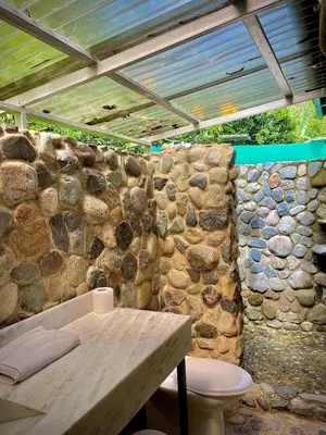 a bathroom with a stone wall and a toilet at Dome #1 in Rivas