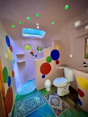 a bathroom with a toilet with a painted wall at Dome 2 in Rivas