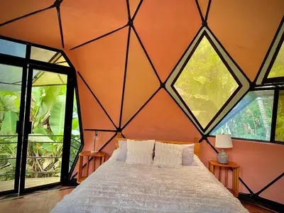 a bedroom with a large bed with large windows at Dome 2 in Rivas