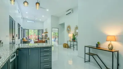 a kitchen with a counter and a living room at Modern Retreat in the Rainforest with River Access in Ojochal